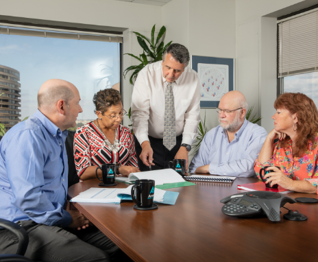 Five people in a business meeting gathered around a table